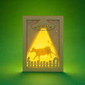 Laser cut shadow box card with a UFO and cow silhouette on a green background