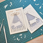 Two laser-cut cards on a green cutting mat with tools.