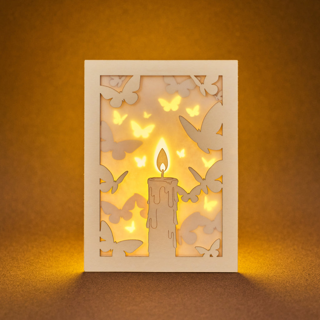 Burning candle with butterflies and moths drawn to flame