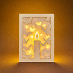 Burning candle with butterflies and moths drawn to flame