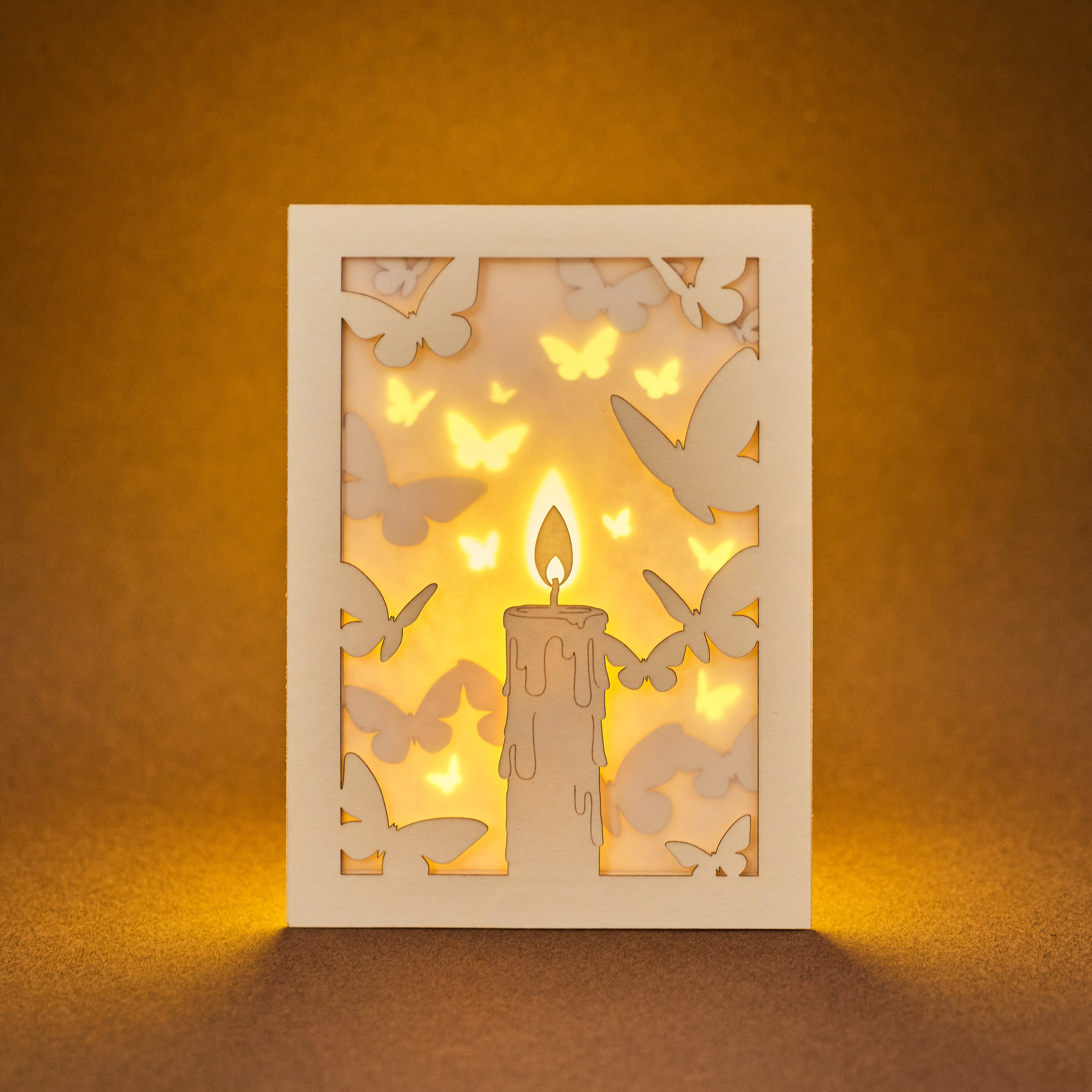 Burning candle with butterflies and moths drawn to flame