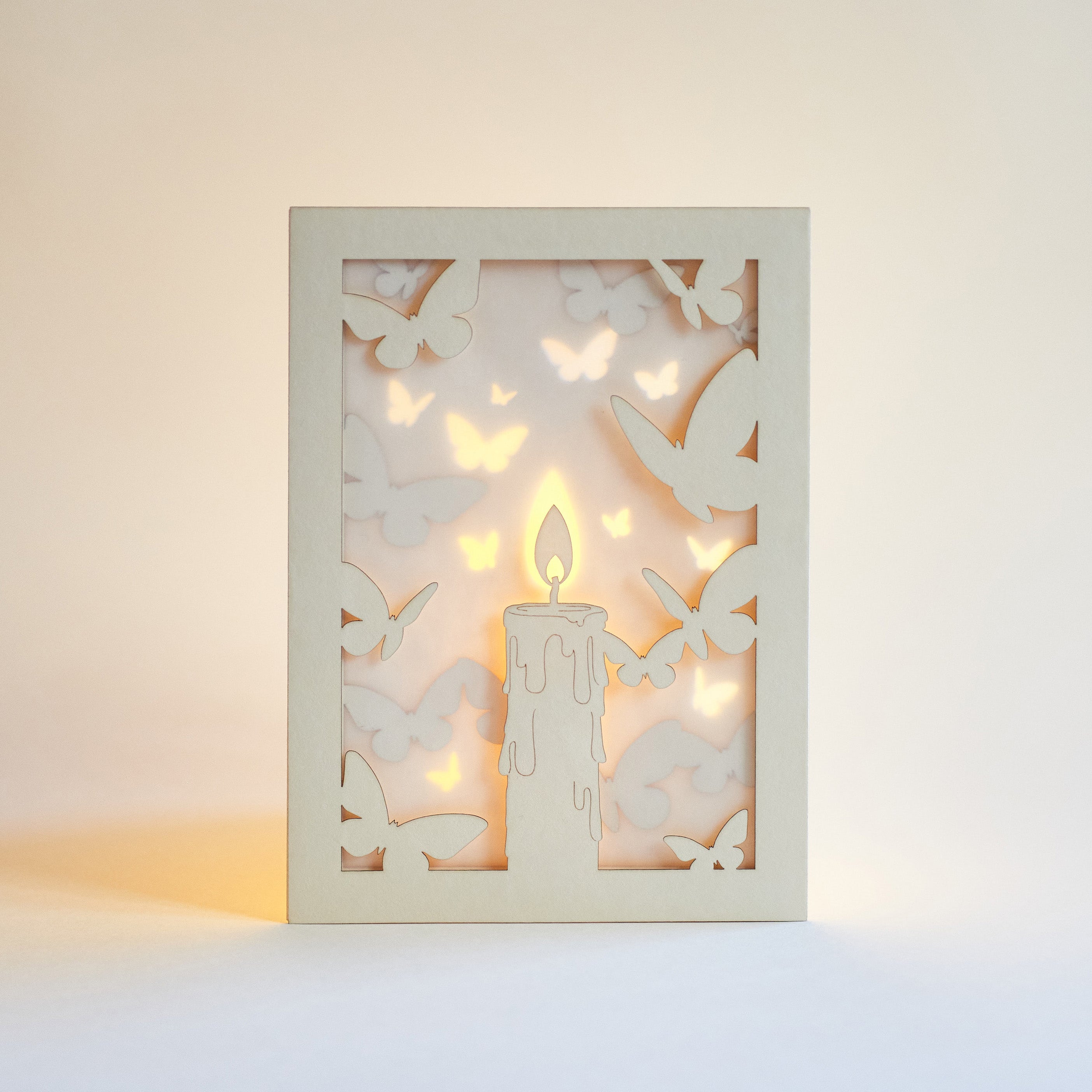 Burning candle with butterflies and moths drawn to flame