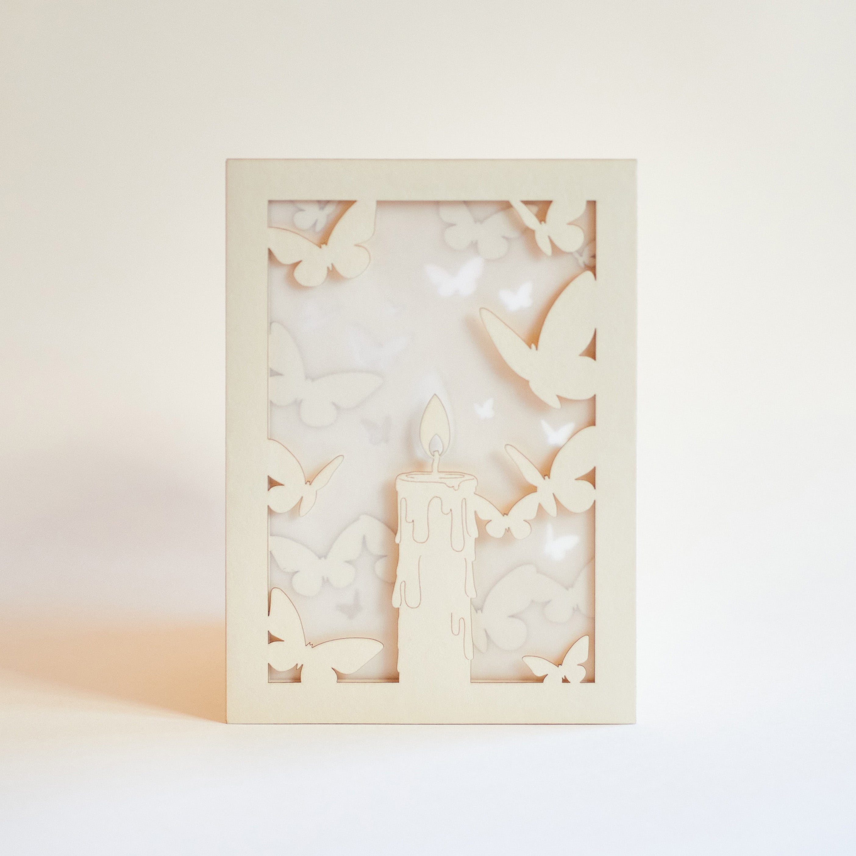 Burning candle with butterflies and moths drawn to flame