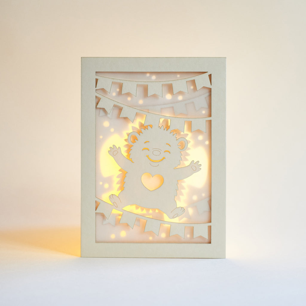 Cute hedgehog making snow angel with festive banner flags