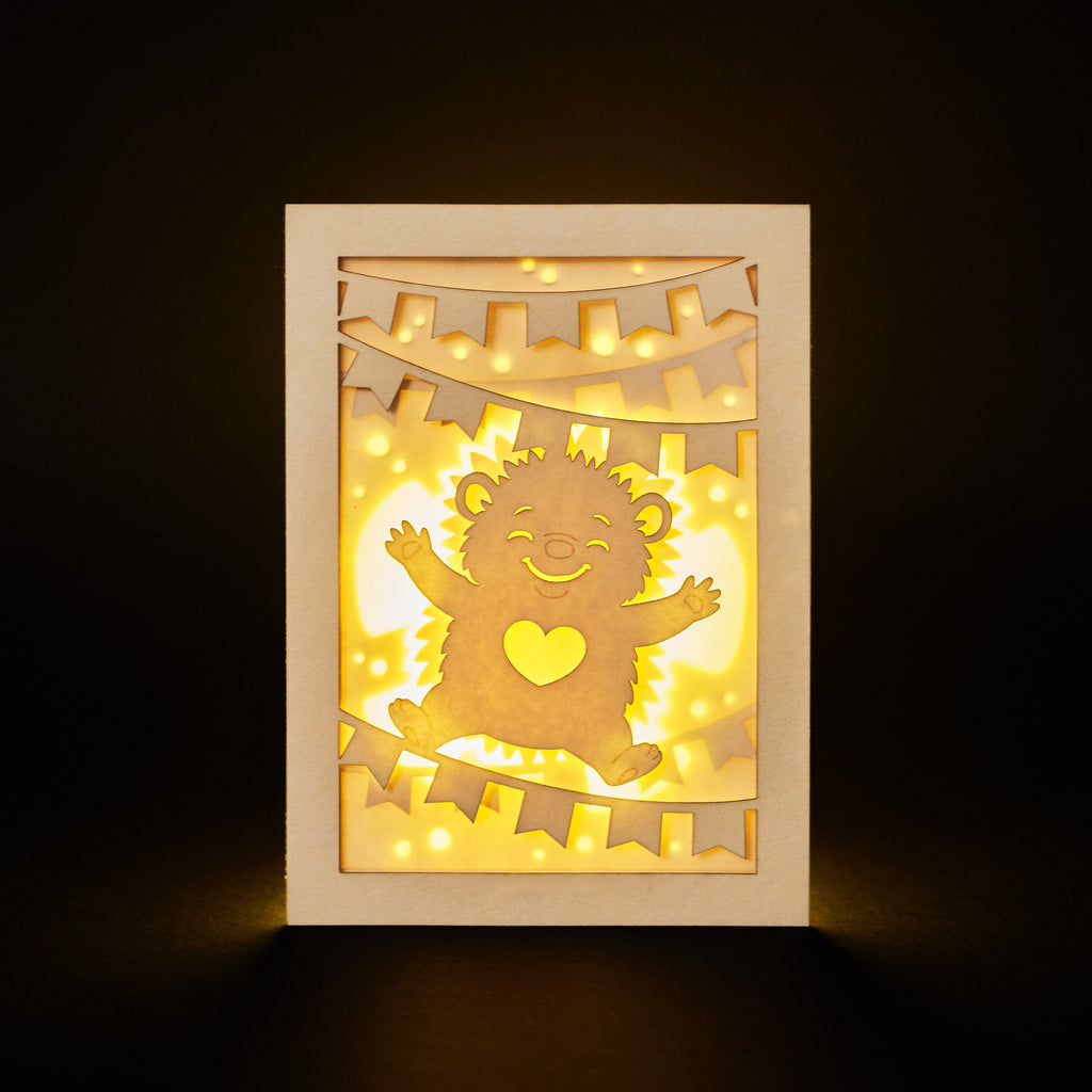 Cute hedgehog making snow angel with festive banner flags