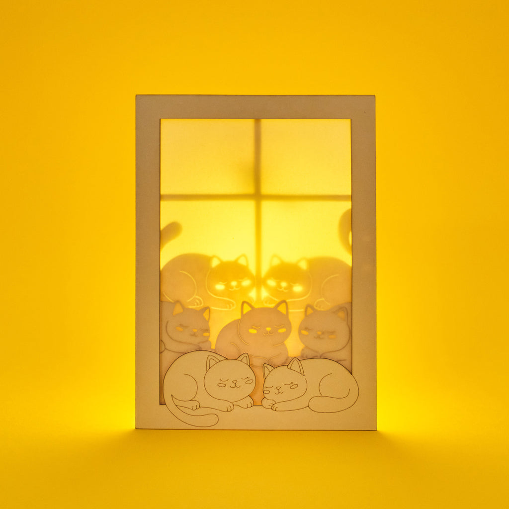 Cats basking on sunny windowsill with closed eyes and tails up