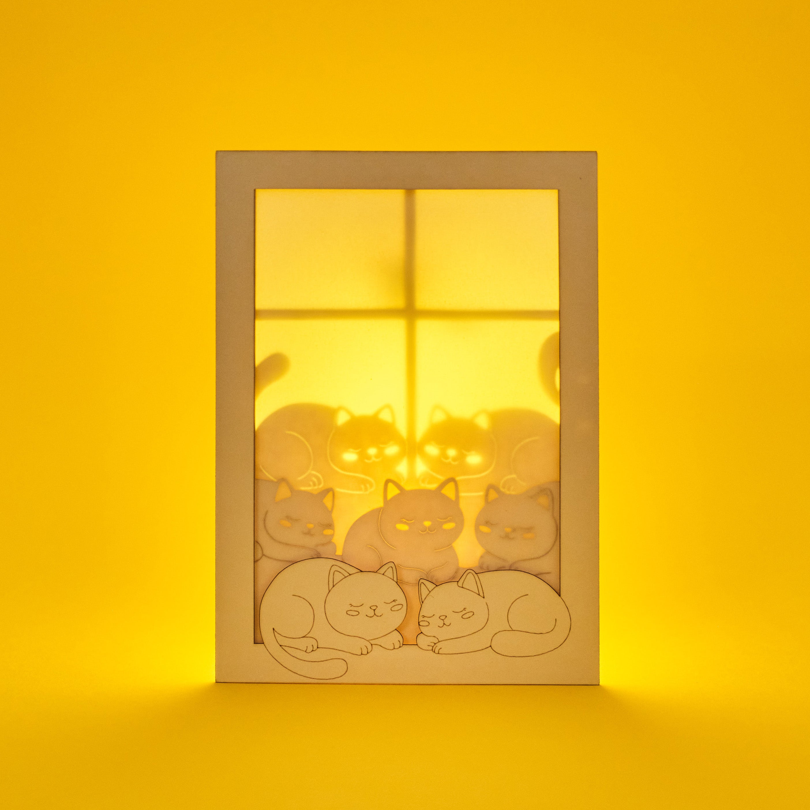 Cats basking on sunny windowsill with closed eyes and tails up