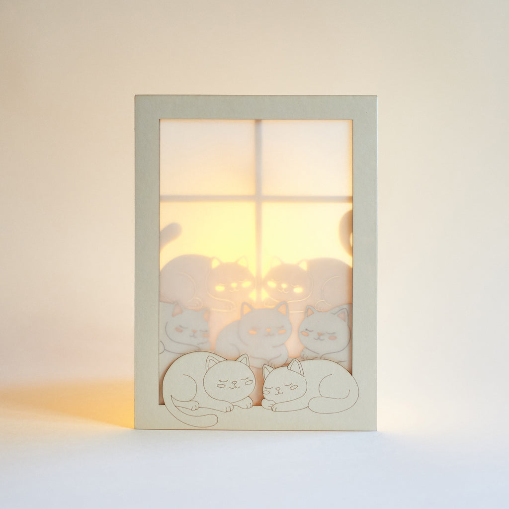 Cats basking on sunny windowsill with closed eyes and tails up