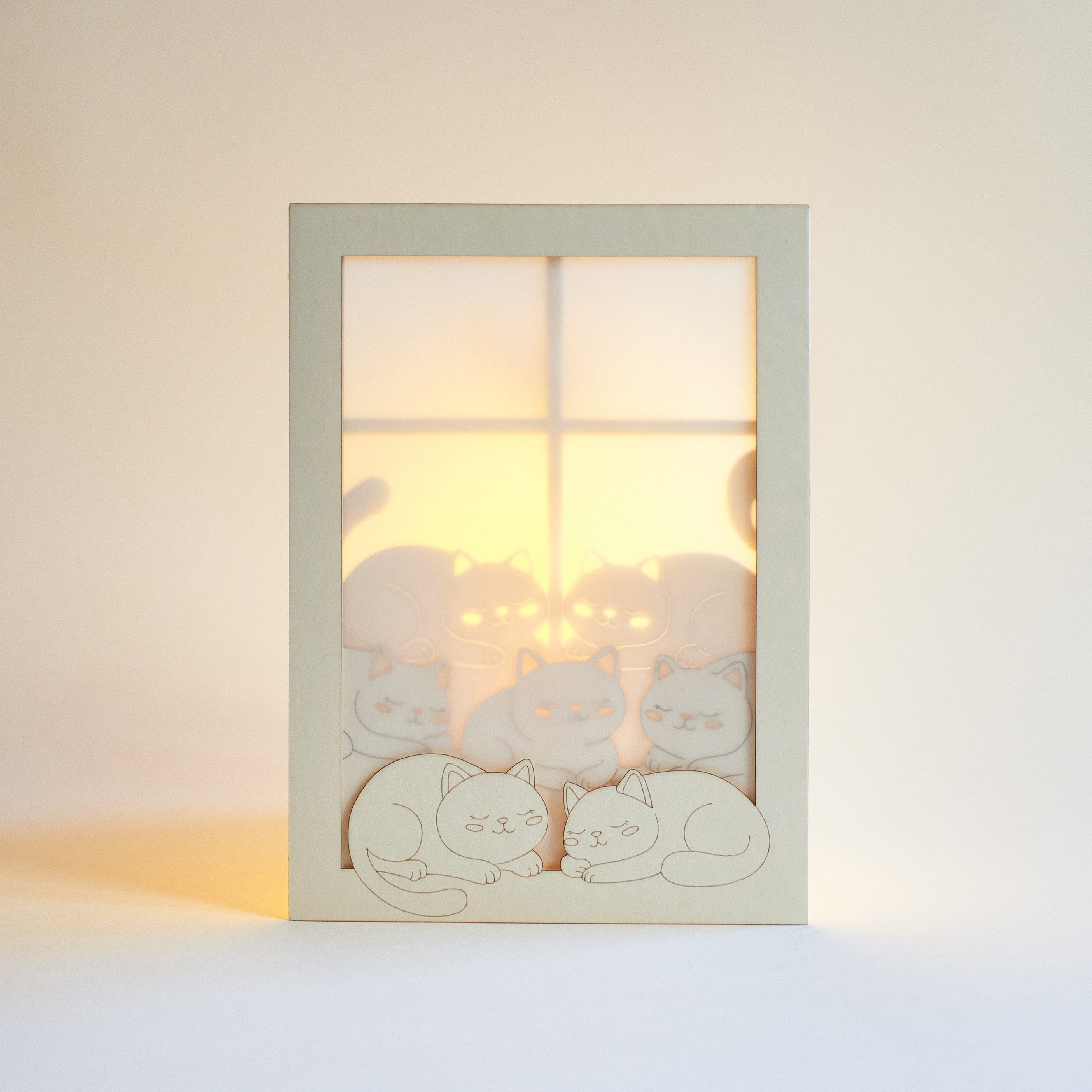 Cats basking on sunny windowsill with closed eyes and tails up