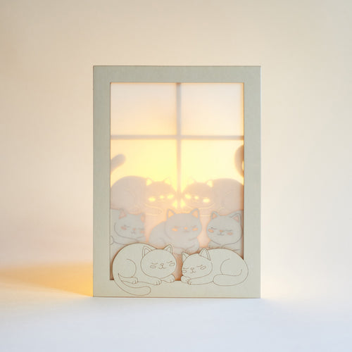 Cats basking on sunny windowsill with closed eyes and tails up