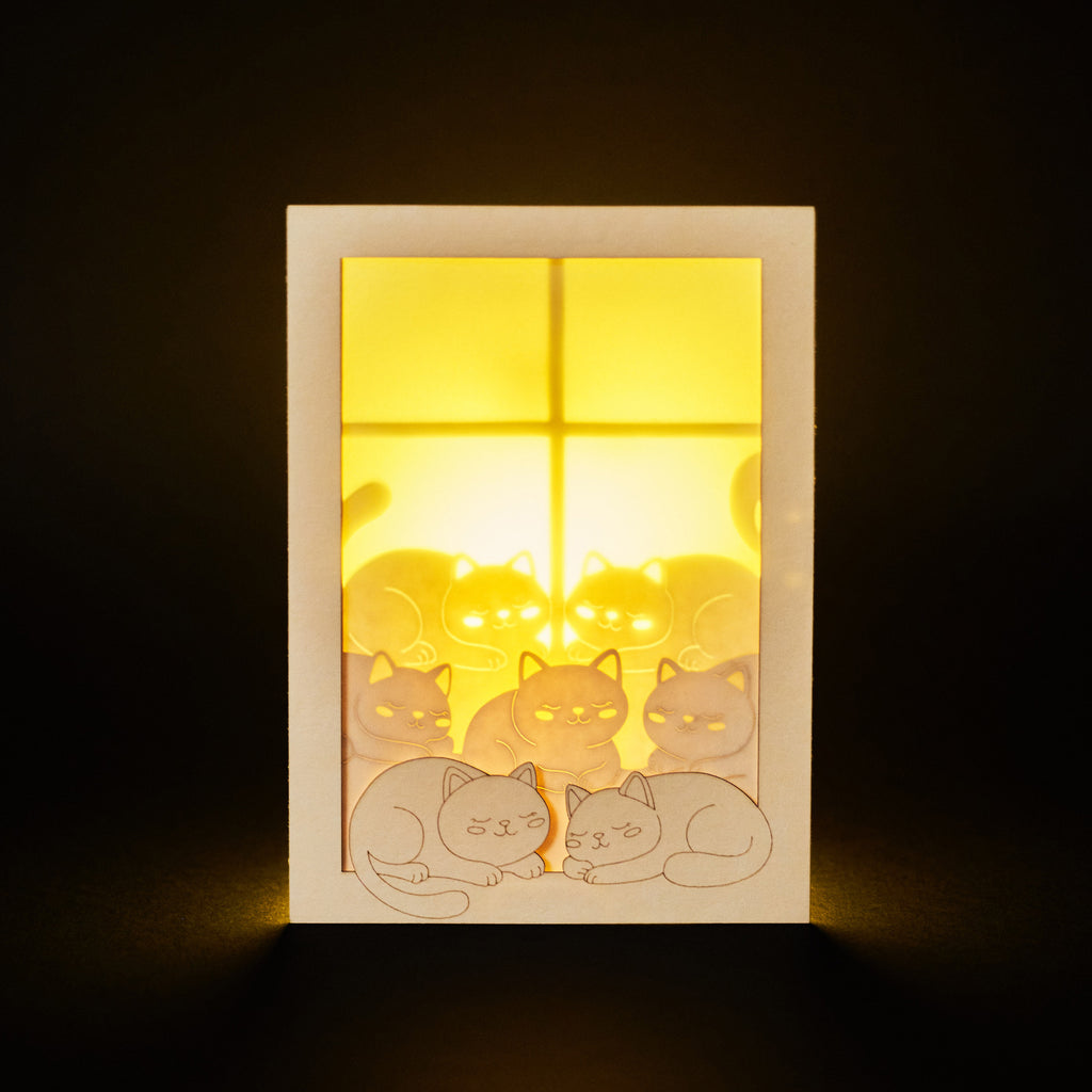 Cats basking on sunny windowsill with closed eyes and tails up