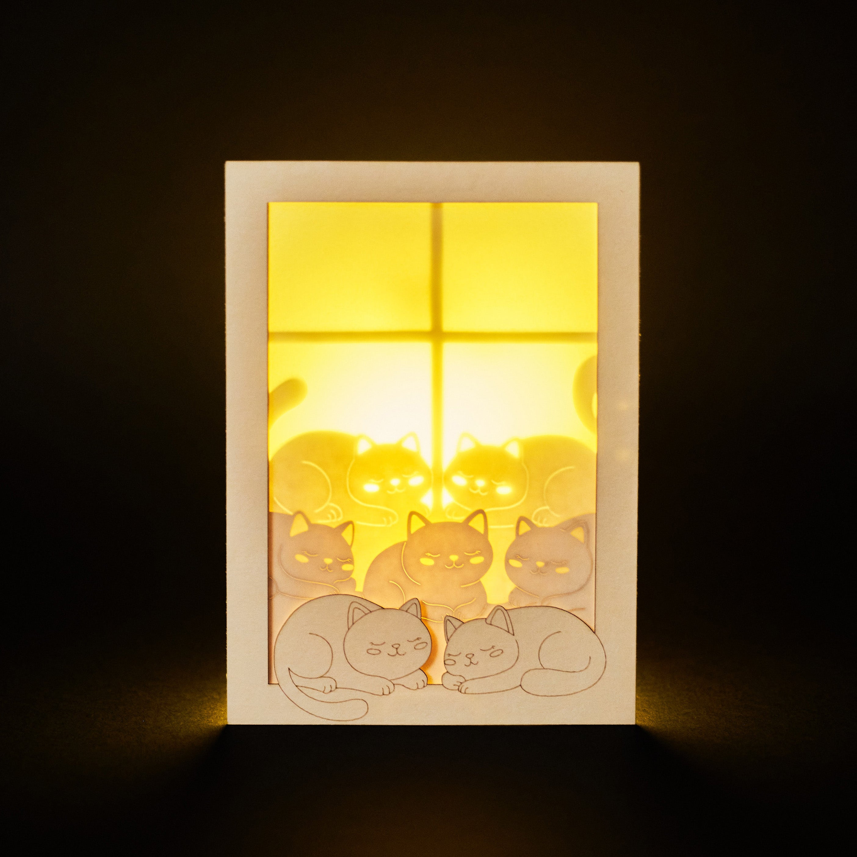 Cats basking on sunny windowsill with closed eyes and tails up