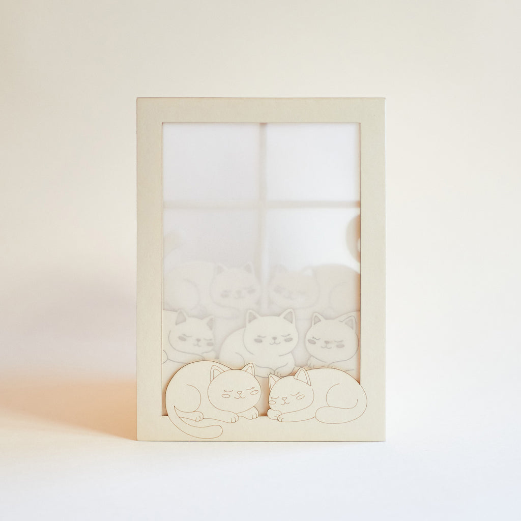 Cats basking on sunny windowsill with closed eyes and tails up