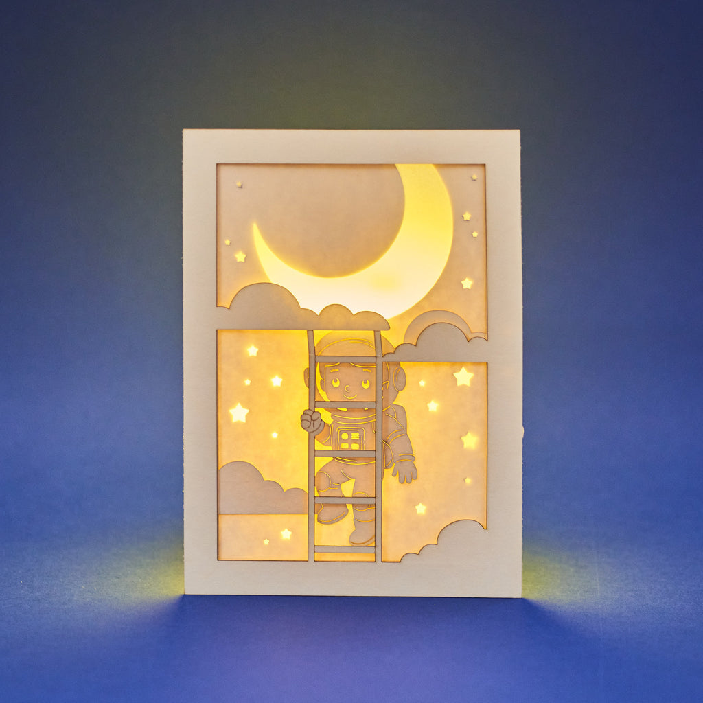 Little boy astronaut climbing ladder to moon and stars