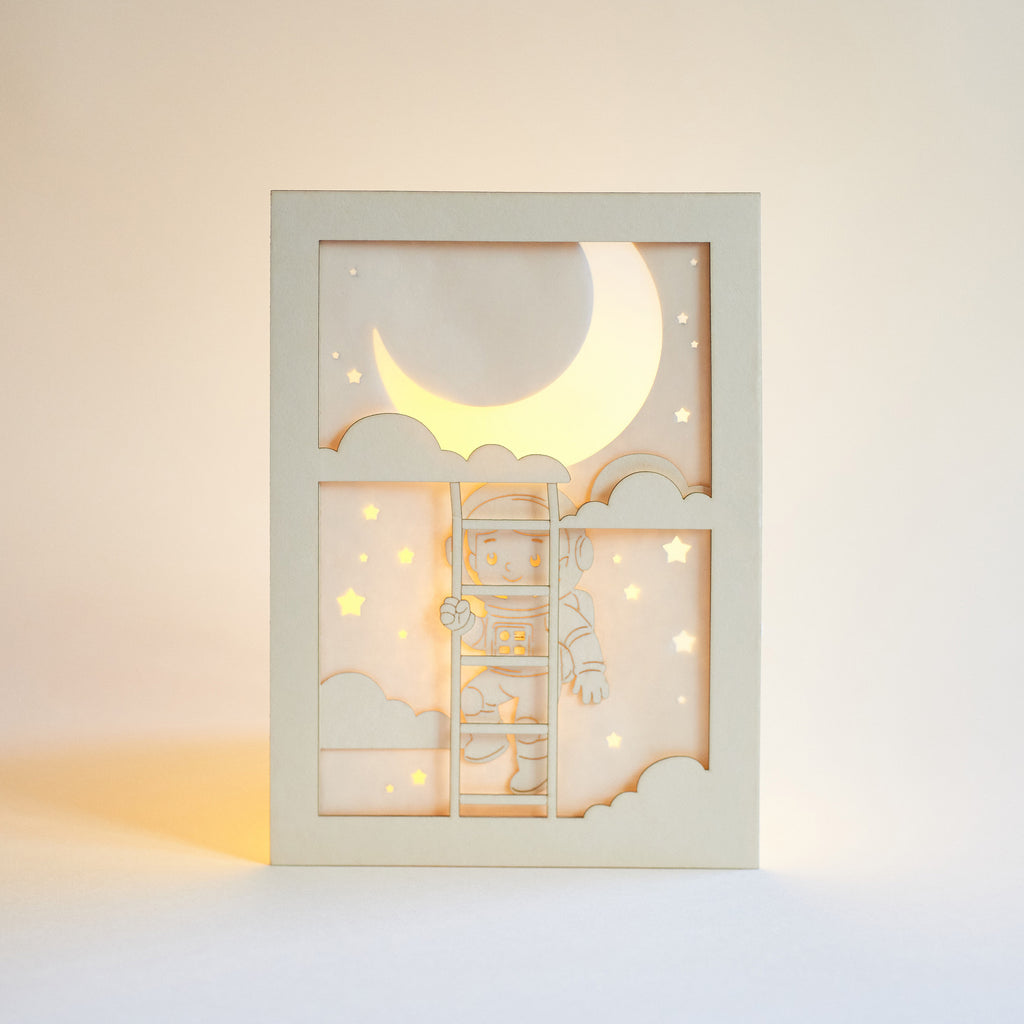 Little boy astronaut climbing ladder to moon and stars