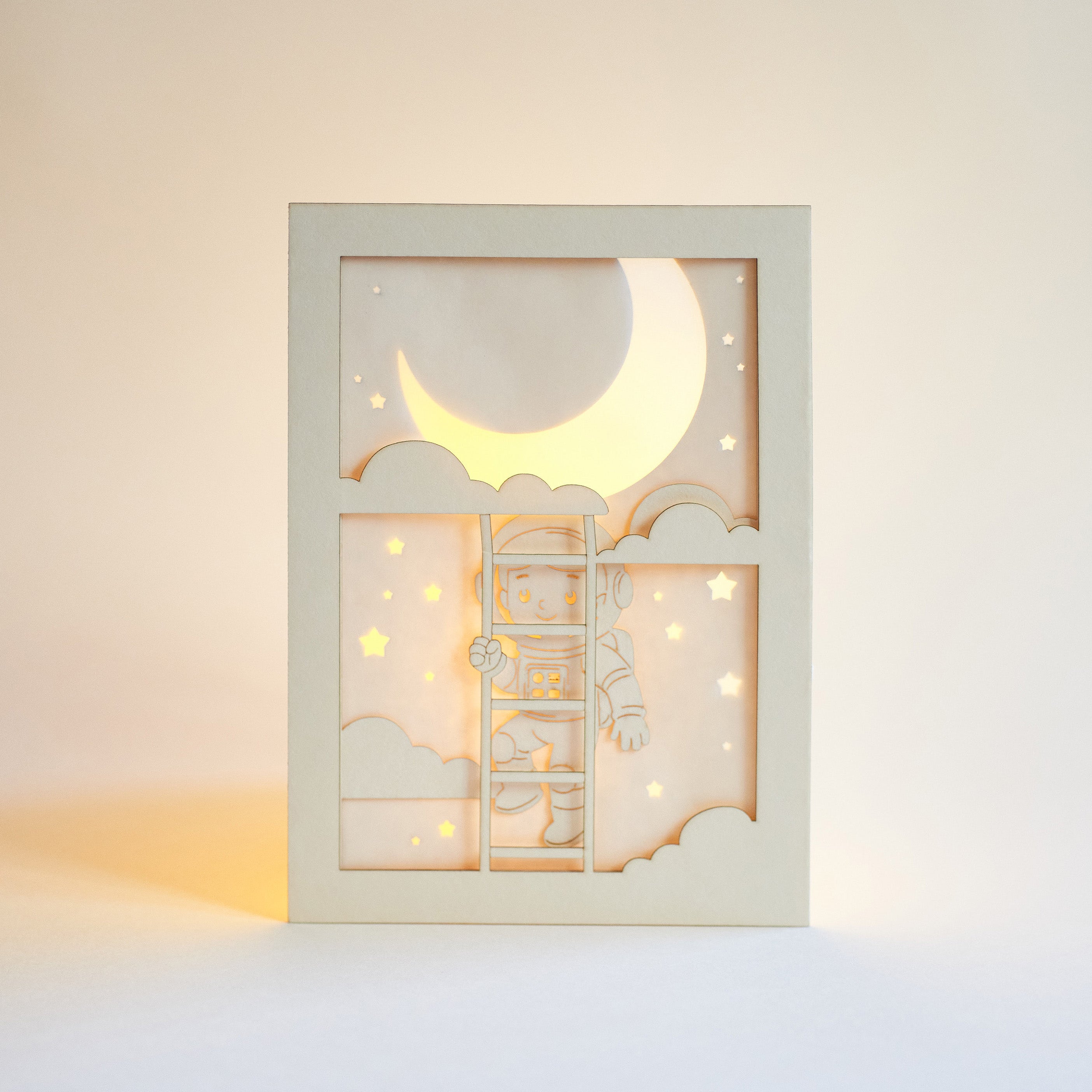 Little boy astronaut climbing ladder to moon and stars