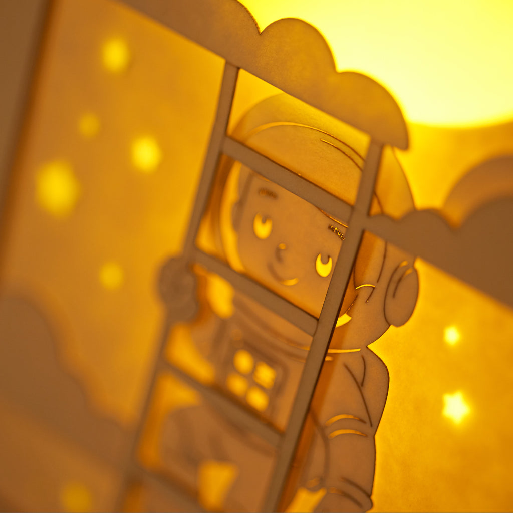 Little boy astronaut climbing ladder to moon and stars