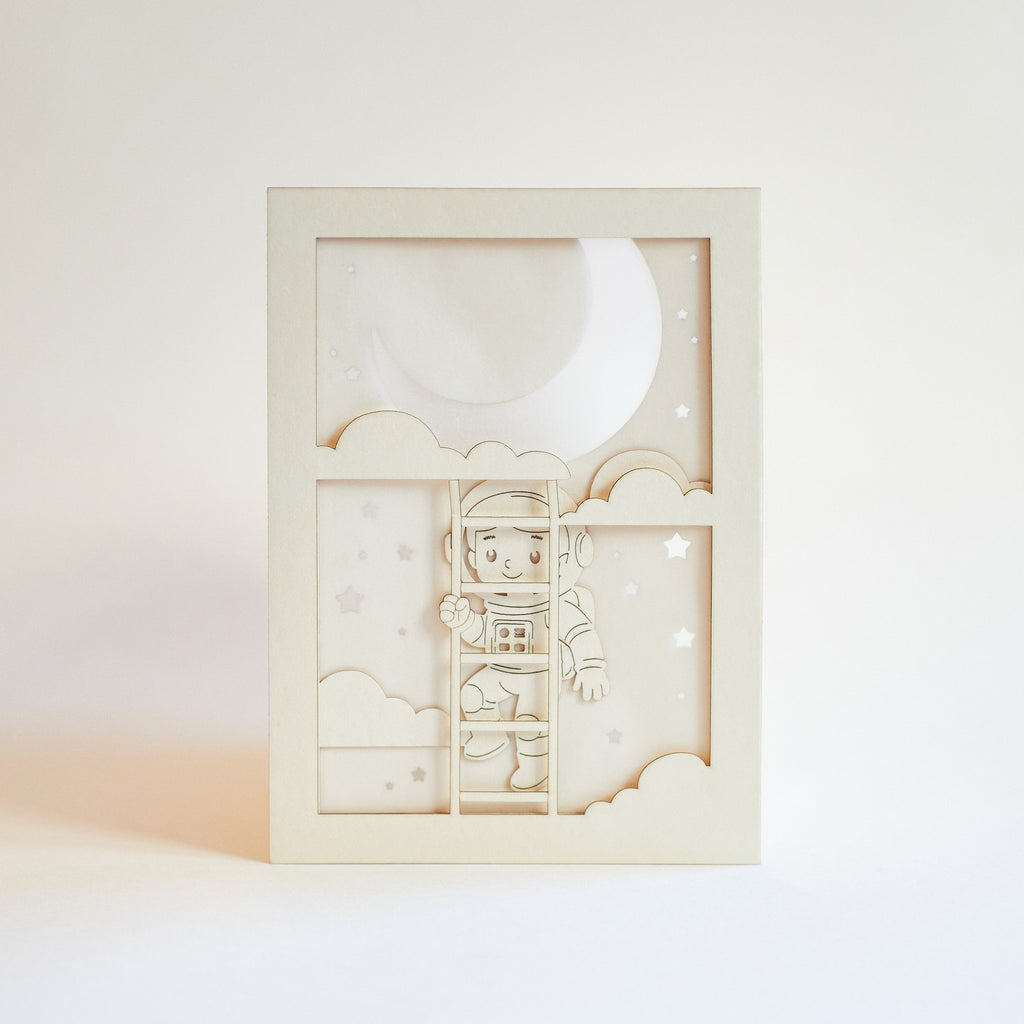 Little boy astronaut climbing ladder to moon and stars