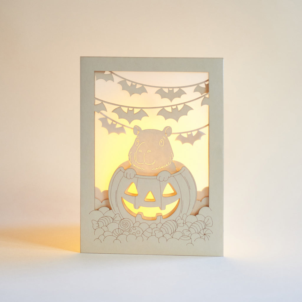 Cute capybara in jack-o-lantern with candy and bats Halloween