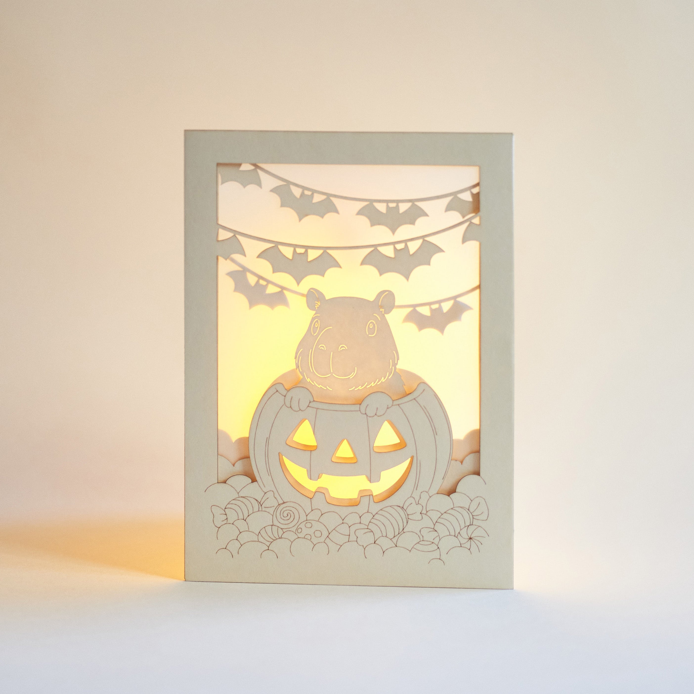 Cute capybara in jack-o-lantern with candy and bats Halloween