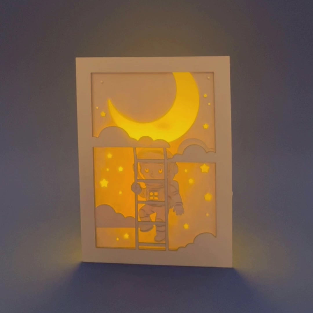 Little boy astronaut climbing ladder to moon and stars