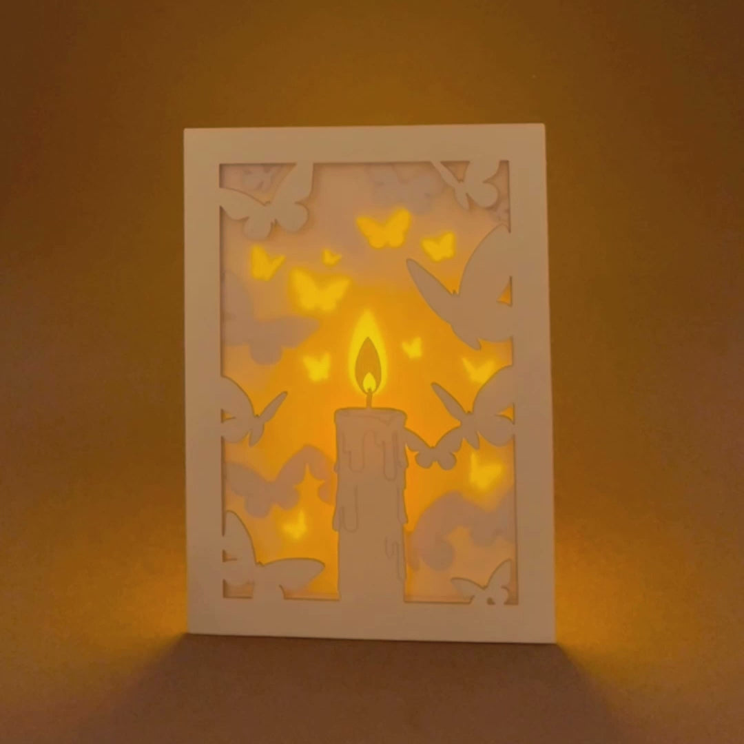 Burning candle with butterflies and moths drawn to flame