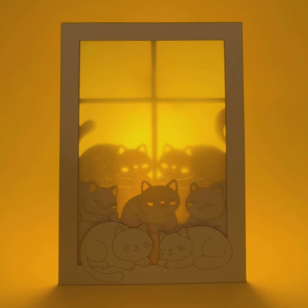 Cats basking on sunny windowsill with closed eyes and tails up